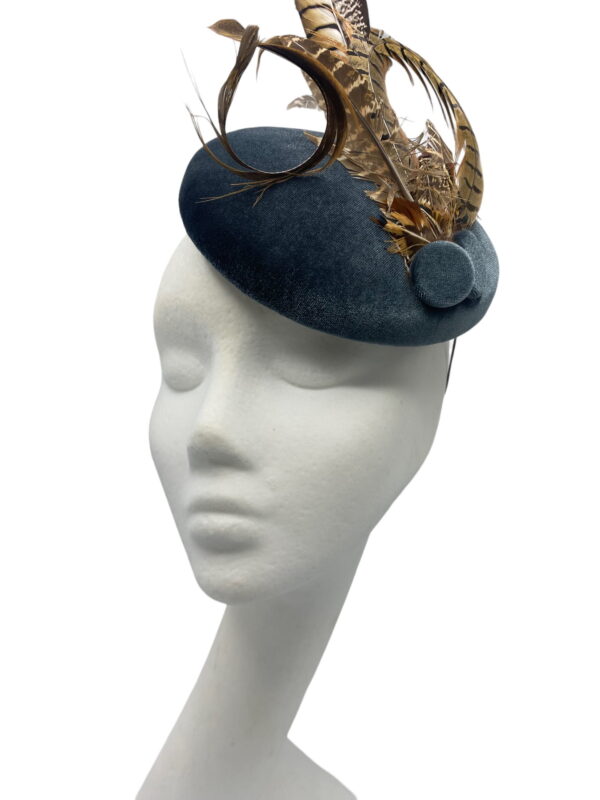Blue/grey velvet headpiece with a spray of brown feathers.